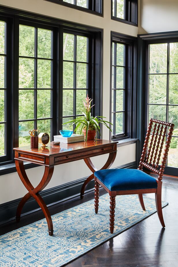 Used judiciously, darker blues—such as the upholstery on this Barton Spindle Side Chair—can accentuate the luxuriousness of dark woods. Choosing a paler blue for the rug keeps the space from feeling visually heavy. Find the desk here. Photo by Frank Frances.
